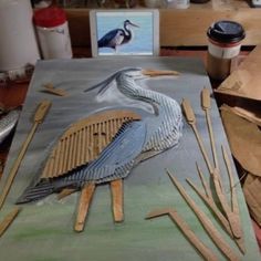 a bird sitting on top of a piece of cardboard next to some wooden spoons