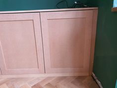 a cat is sitting on the floor in front of some cupboards that are made out of plywood