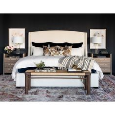 a bedroom with black walls, white bedding and lots of pillows on the headboard