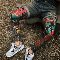 a person sitting on the ground with tattoos on their legs and leggings that are covered in flowers