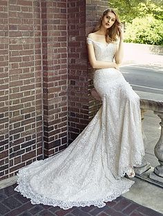 a woman in a wedding dress leaning against a brick wall