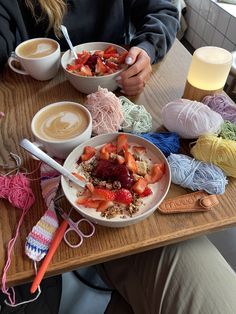 a person sitting at a table with two bowls of food and yarn on the table