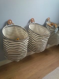 three black and white striped baskets hanging on the side of a blue wall next to a wooden floor