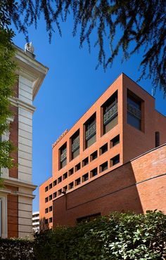 the building is made of red bricks and has many windows on each side, along with a clock tower