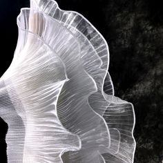 an abstract white sculpture is shown against a dark background