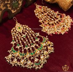 two pairs of gold and green earrings on a red velvet surface with golden jewelry pieces in the background