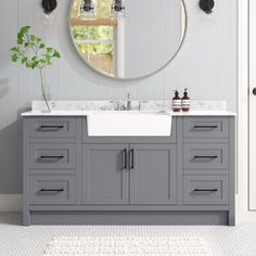 a bathroom with gray cabinets and a round mirror