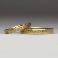 two gold wedding bands sitting next to each other