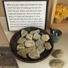 a bowl full of rocks with writing on them next to a sign that says what are your hopes and dreams for your child not only for children