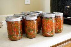 six jars filled with food sitting on top of a counter next to an open oven