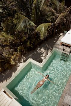 a woman in a swimming pool surrounded by palm trees