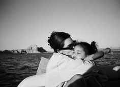 a woman holding a child on the back of a boat