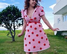 a woman in a pink dress is standing on the grass with her hands out to the side