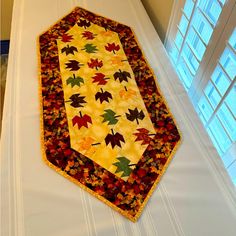 a quilted table runner with autumn leaves on it