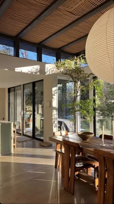 a dining room with large windows and wooden table surrounded by chairs in front of an open floor plan