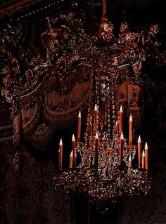 a chandelier with many lit candles hanging from it's sides in a dark room