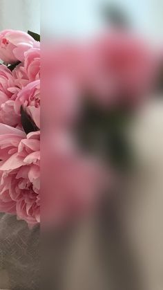 pink flowers are in a vase on a table with a white cloth around it and the bottom half of the photo is blurry