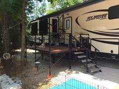 an rv parked in the woods with stairs leading up to it