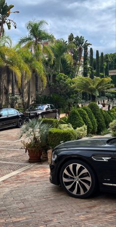 a black car parked on the side of a road next to some trees and bushes