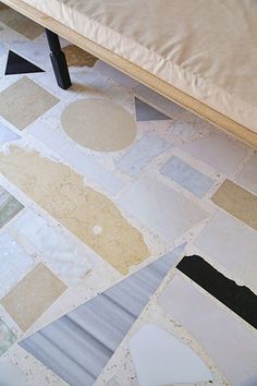 a bed sitting on top of a tiled floor next to a wall