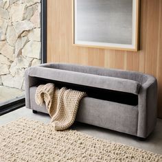 a gray couch sitting next to a window with a blanket on it