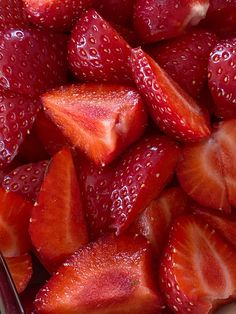 sliced strawberries sit in a bowl on the table