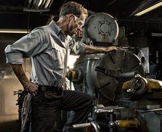 a man standing next to a machine in a factory with his hands on his hips