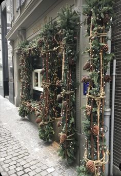 christmas decorations on the side of a building with lights and pine cones hanging from it