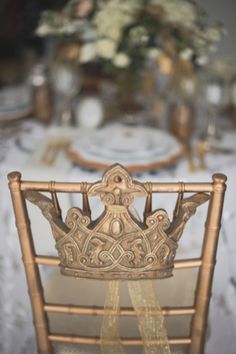 a chair with a crown on it sitting in front of a table set for dinner