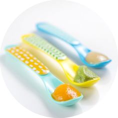 three toothbrushes are lined up on a white surface with oranges and avocado