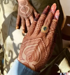 a woman's hand with henna on it and an ornate ring in the middle