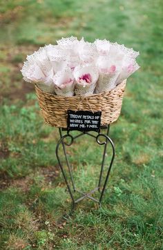 a basket filled with pink flowers sitting on top of a metal stand in the grass