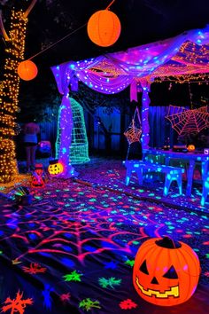 an outdoor halloween party with pumpkins, lights and decorations on the ground at night