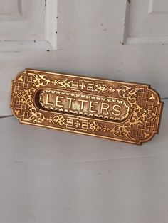 a door handle with the word letters written in gold on white painted wood paneling