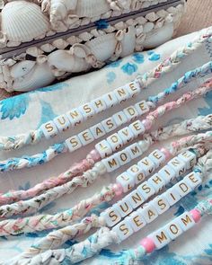 four bracelets with words written on them sitting next to shells and seashells