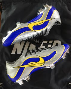 a pair of nike shoes sitting on top of a black and blue bag with the word nike written on it