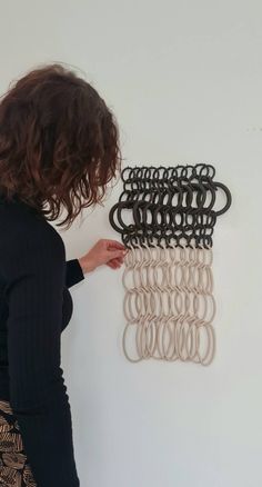 a woman standing in front of a wall with several pieces of art hanging on it