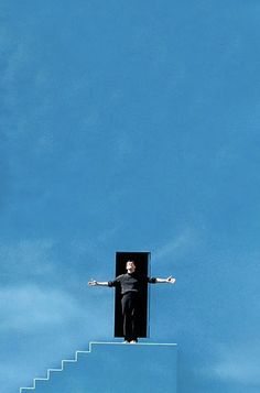 a man standing on top of a stair case with his arms outstretched in the air