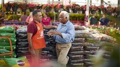 two men standing next to each other in a garden center