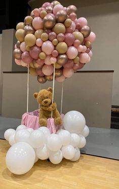 a teddy bear sitting on top of a bunch of balloons