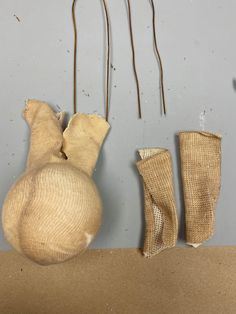 three pieces of cloth hanging from hooks on a gray wall next to two burlocks