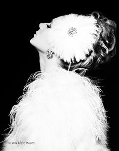 black and white photograph of a woman wearing a feathered dress with jewels on her head