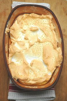 a dish filled with food sitting on top of a wooden table next to a napkin