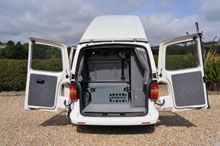 the back end of a white van with its doors open and two speakers on it