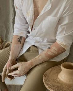 a man sitting down with his hands covered in mud