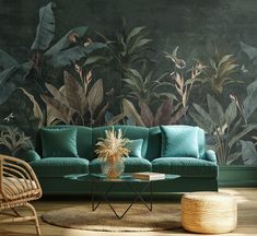 a living room with a blue couch and large green leaves on the wall behind it