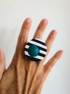 a person's hand with a ring on it that has an oval and striped design