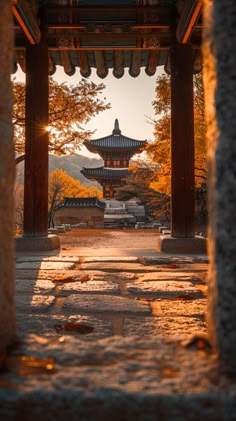 the sun shines brightly through an archway in front of a pagoda with trees around it