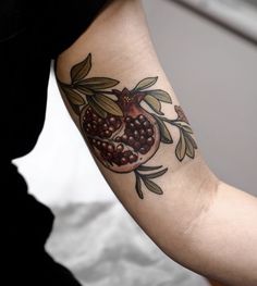 a woman's arm with a pomegranate and leaves tattoo on it