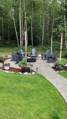 an outdoor patio with chairs and fire pit surrounded by trees in the middle of a grassy area